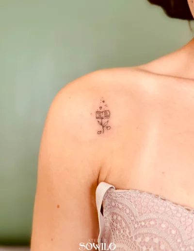 Tatouage épaule femme, personnalisé, représentant un livre et des coeurs fait par L'Atelier Sowilo à Clisson en Loire Atlantique, type fin et minimaliste
