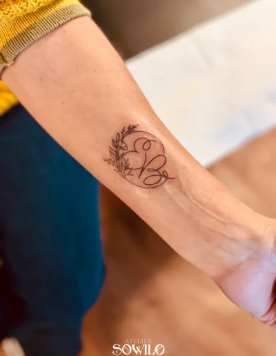 Tatouage avant bras, femme , représentant un bouquet de fleurs avec des lettres fait par l'Atelier Sowilo