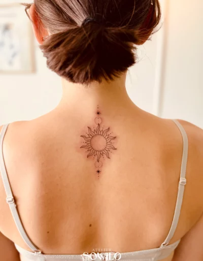 Tatouage représentant un soleil et des étoiles, géométrique, trait fin et minimaliste dans le dos d'une femme