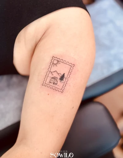 Tatouage avant bras, femme , représentant un timbre avec une montagne soleil et van, ambiance road trip fait par l'Atelier Sowilo