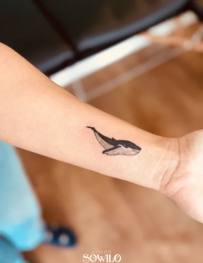Tatouage baleine enfantine, sur l'avant bras d'une femme